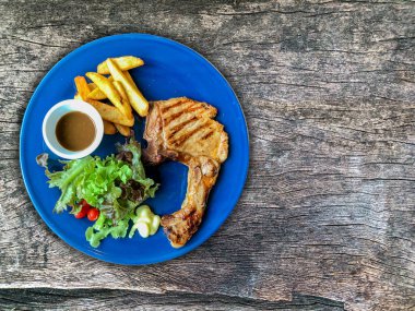 Tabakta biftek ve ahşap arka plan.