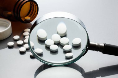 Büyüteç, tabletler ve şişe üzerinde gri yansıma backgrou