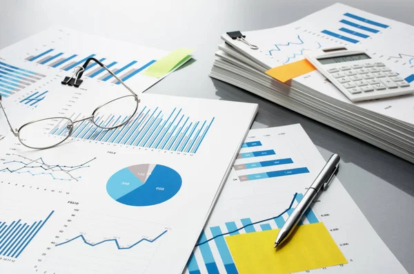Erstellung eines Berichts. Blaue Graphen, Brille, Taschenrechner und Stift. — Stockfoto