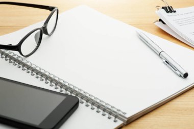 Parlak ahşap masa üstünde açık defter. 