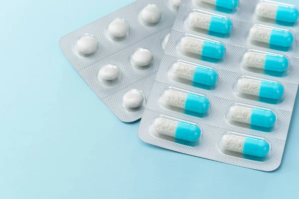 Синие капсулы лекарства и таблетки на голубом фоне . — стоковое фото