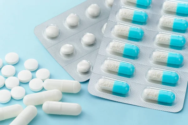 Многие капсульные лекарства и таблетки на голубом фоне . — стоковое фото