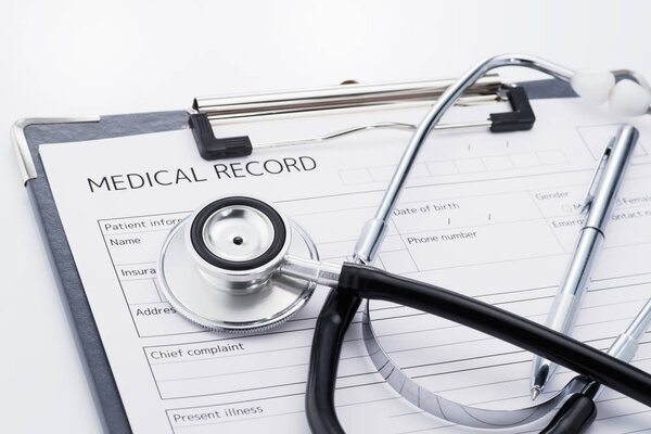 Stethoscope and medical record on white background.