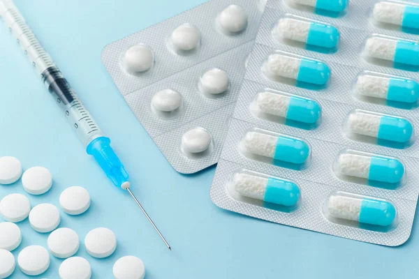 Muitos medicamentos para cápsulas, seringas para injectáveis e comprimidos nas costas azuis — Fotografia de Stock
