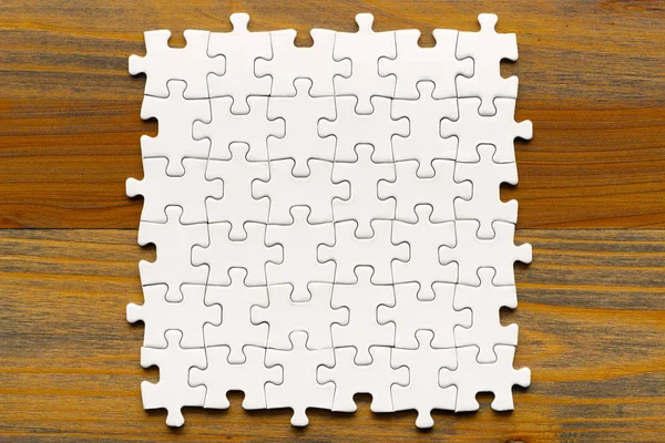 Puzzel achtergrond. Witte stukken op houten tafel. — Stockfoto