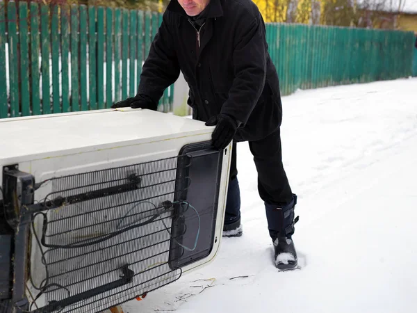 Man pushing a fridge outdoor