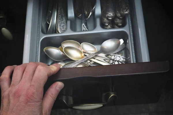 Hand opening a cupboard with vintage silverware, indoor closeup