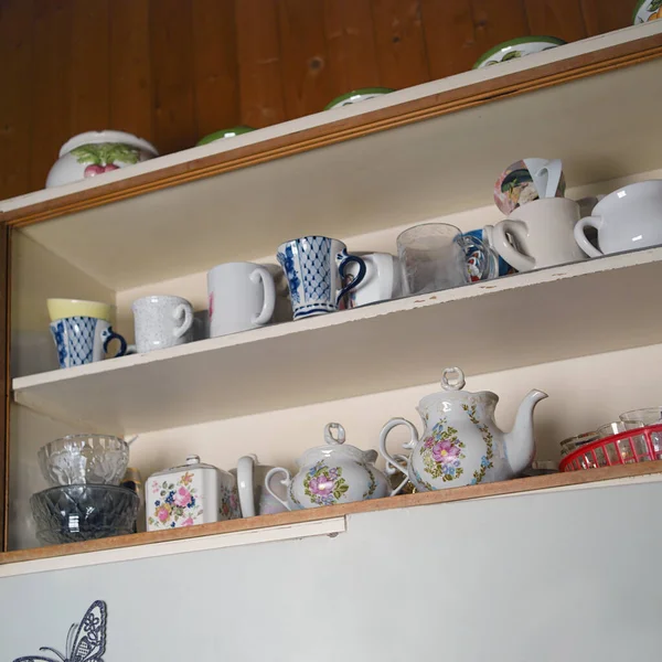 A cupboard with collection of kitchenware on the shelves, indoor angled shot