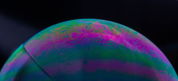 Красивый полупрозрачный мыльный пузырь на тёмном фоне
