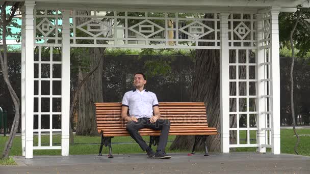 Hombre feliz solo sentado en el banco del parque — Vídeo de stock