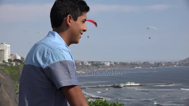 Мальчик-подросток наблюдает за парасейлингом — стоковое видео