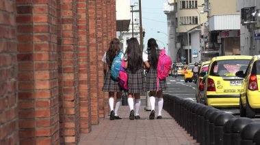 Lise öğrencilerinin kaldırımda yürüyen sırt çantaları ile