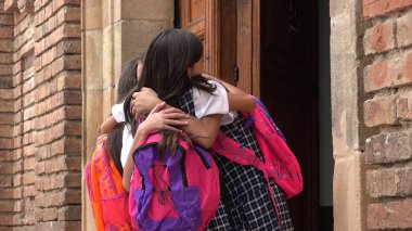 Sırt çantaları giyen İspanyol kız öğrenciler sarılma