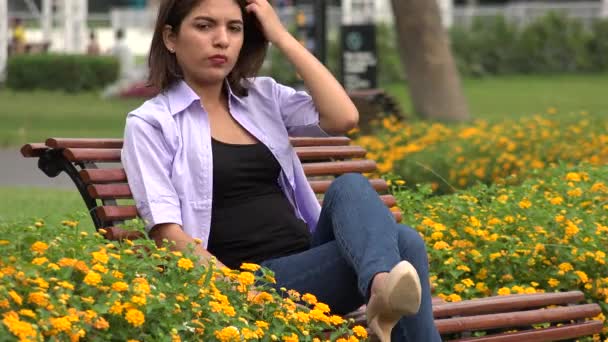 Weiblicher Teenager sitzt auf Parkbank — Stockvideo