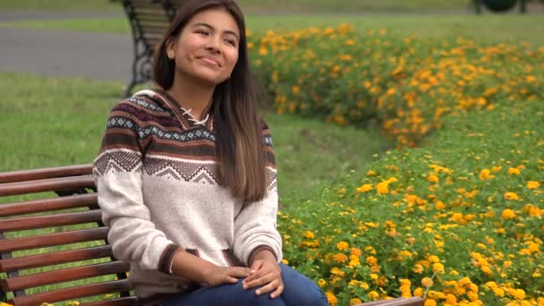 Счастливый латиноамериканский подросток, сидящий в парке — стоковое видео