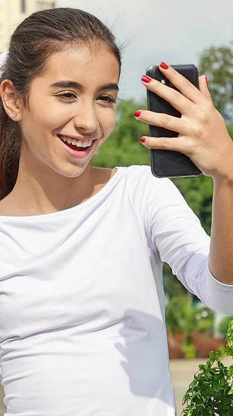 Vackra tonåriga kvinna med hjälp av mobiltelefon och glad — Stockfoto