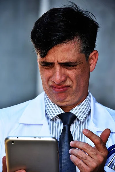 Confused Male Doctor Wearing Lab Coat With Tablet