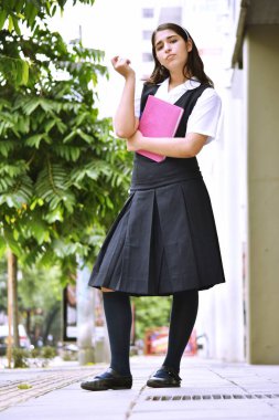 Heyecansız şirin Kolombiya kız öğrencinin okul üniforması ile defter