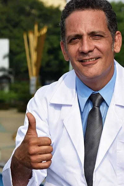 Schöner männlicher Arzt mit hochgereckten Daumen im Laborkittel — Stockfoto