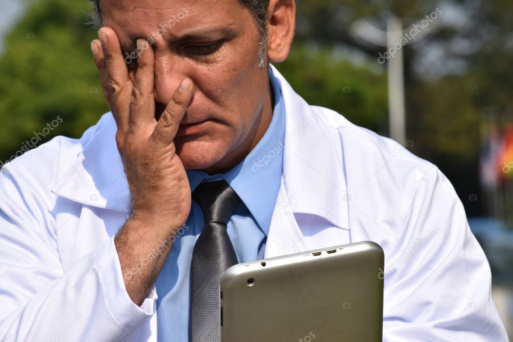 Male Hispanic Doctor Using Tablet And Confusion