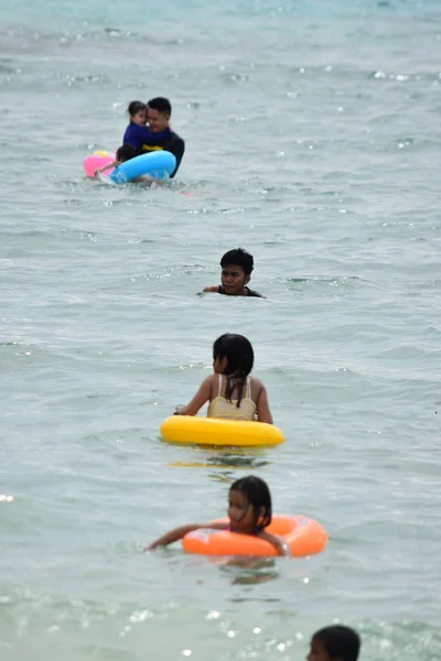 Люди, плавающие в воде на пляже летом — стоковое фото