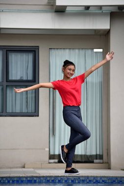 Genç bir kız ayakta eğleniyor.