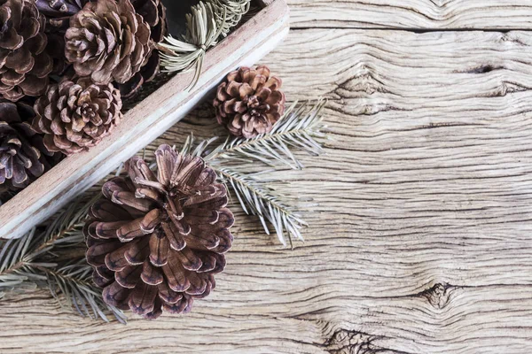 Рождественское украшение сосновых шишек в деревянной коробке — стоковое фото