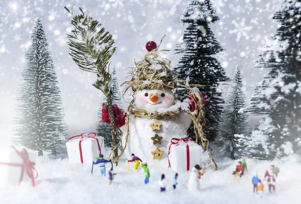 Boneco de neve e pessoas em florestas de pinheiros durante o inverno — Fotografia de Stock