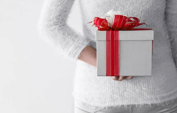 Mujer joven escondiendo caja de regalo de plata detrás de su espalda — Foto de Stock