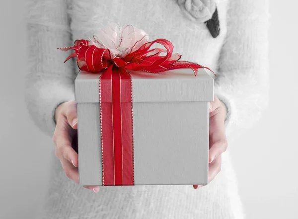 Kırmızı ve beyaz kaburga ile gümüş hediye kutusu tutan eller genç kadın — Stok fotoğraf