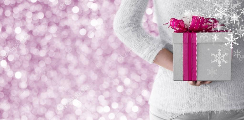 Young woman hiding silver gift box behind her back