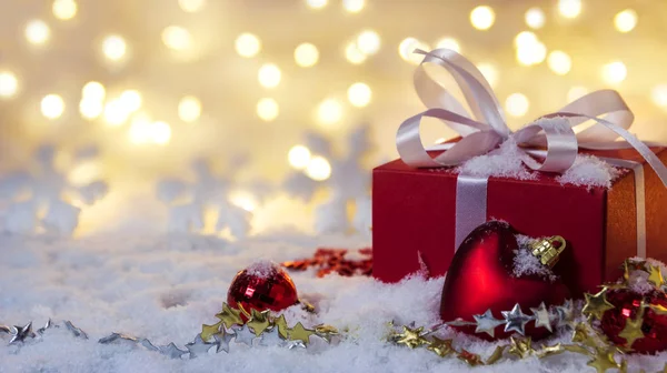 Red gift box on snow with bokeh background — Stock Photo, Image