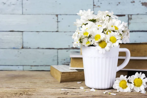 Flores frescas da margarida em copo branco na mesa de madeira — Fotografia de Stock