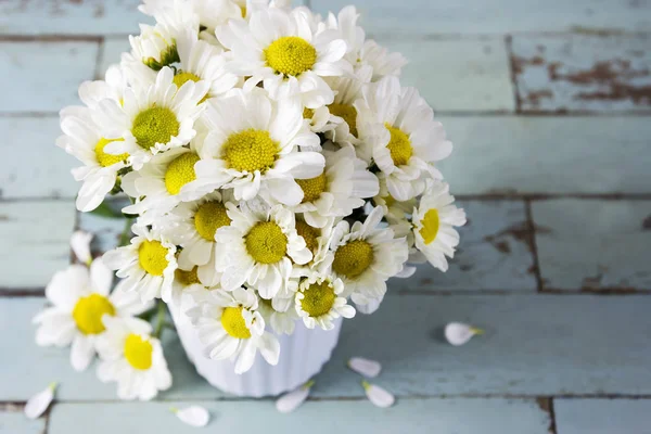 在木制的桌子上的白色杯新鲜的雏菊花 — 图库照片
