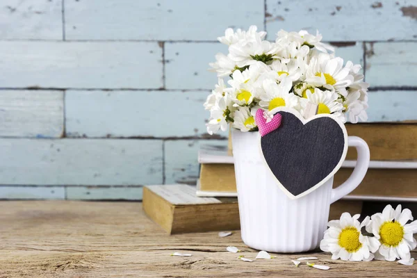 Flores de margarita en copa blanca con corazón de madera en blanco — Foto de Stock
