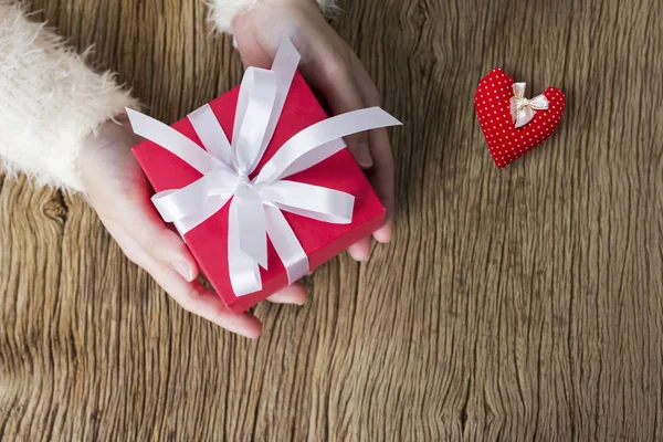 Руки девушки держат красную подарочную коробку и красное сердце — стоковое фото