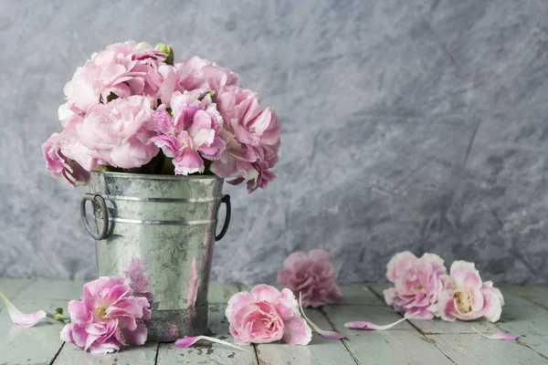 Pink carnation flowers in zinc bucket on old wood — Stock Photo, Image