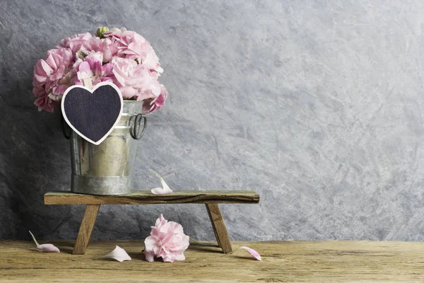 Flores de clavel rosa en cubo de zinc con corazón de madera en blanco —  Fotos de Stock