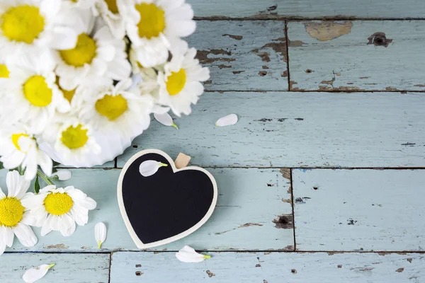 Corazón de madera en blanco y flores de margarita en madera vieja — Foto de Stock