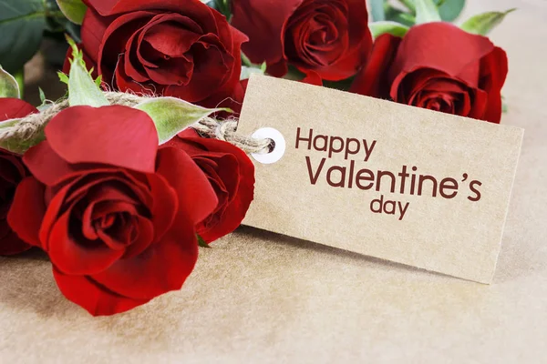 Rosas vermelhas com cartão de Dia dos Namorados em papel marrom — Fotografia de Stock