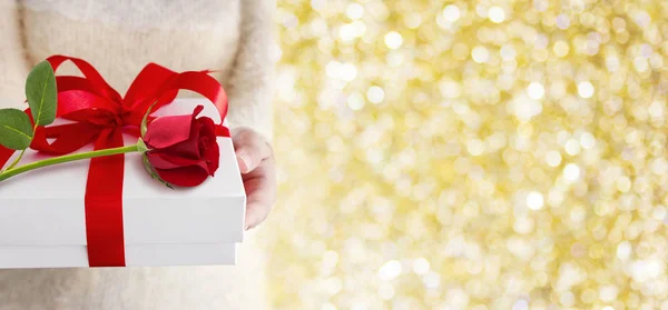 Beyaz hediye kutusu ve kırmızı gül tutan eller genç kadın — Stok fotoğraf