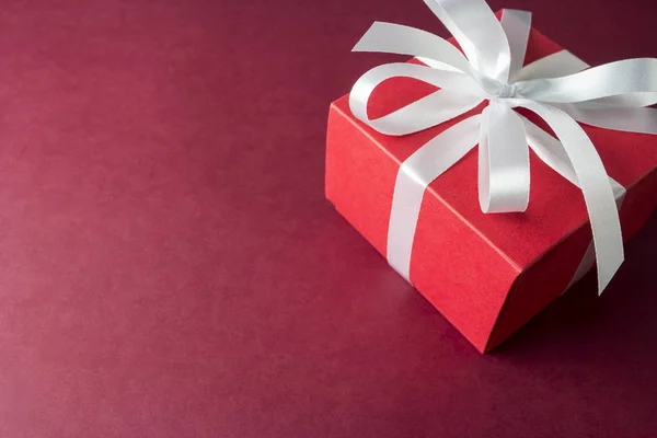 Piros ajándék doboz, papír alapon fehér szalaggal — Stock Fotó