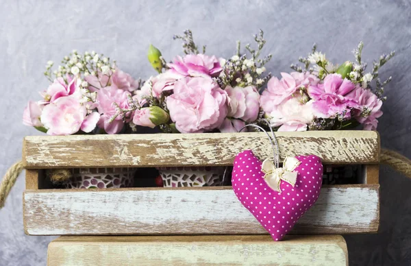 Rosa Herz mit Schleife und Nelkenblüten in Holzkiste — Stockfoto