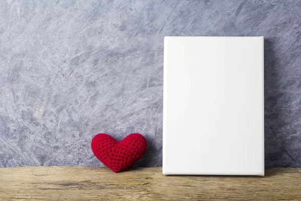 Liebeskonzepte aus rotem Herz und leerem Leinwandrahmen auf Holztisch für Valentinstag und Hochzeit — Stockfoto