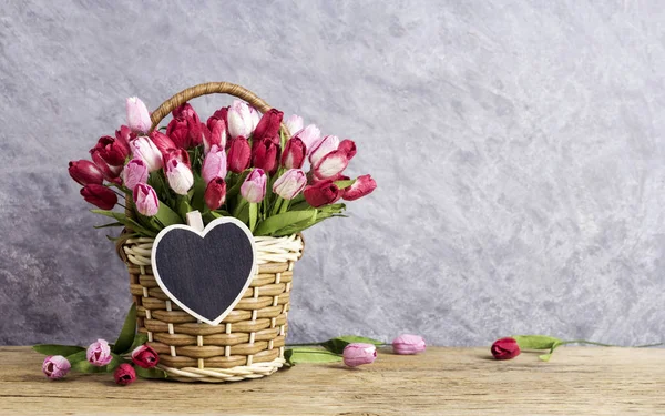 Flores de tulipa rosa e vermelha em cesta de madeira com coração de madeira em branco — Fotografia de Stock