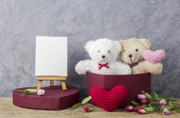Love concept of teddy bear in red heart gift box on wood table and blank canvas frame on easel painting for valentines day and wedding — Stock Photo, Image