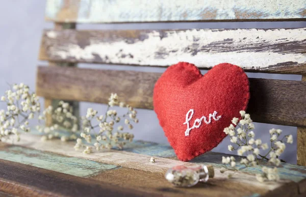 Amor y San Valentín concepto de corazón de fieltro rojo y flores de gypsophila en silla vintage — Foto de Stock