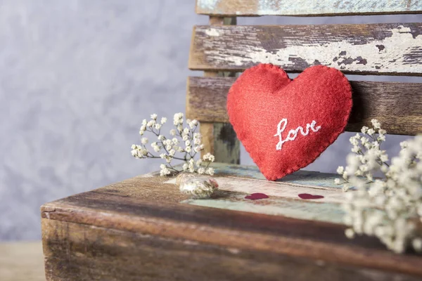 Love and valentines day concept of red felt heart and gypsophila flowers on vintage chair — Stock Photo, Image