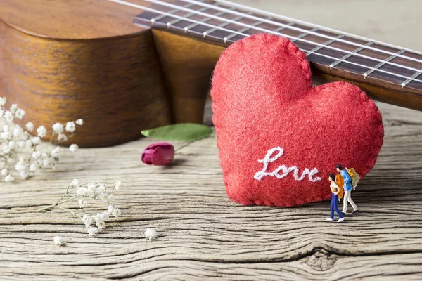 Concepto de amor de mochilero en miniatura pareja y ukelele con corazón rojo en madera vieja — Foto de Stock