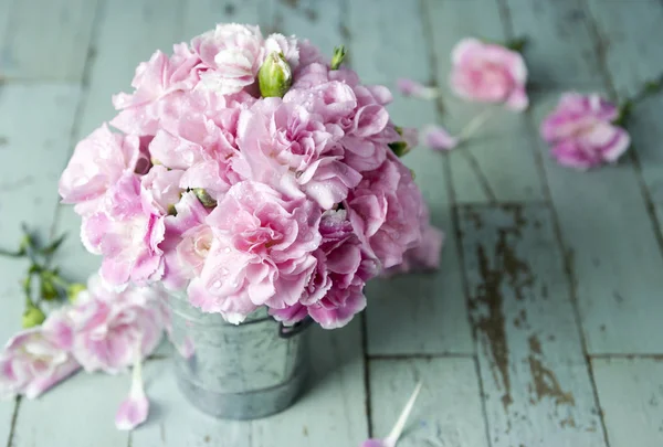 Pink carnation flowers in zinc bucket on vintage wood — Stock Photo, Image